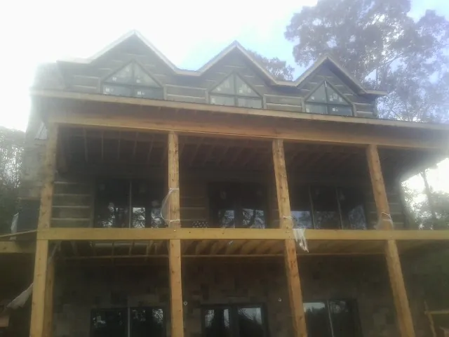 Dormers and porch framing on a large log home under construction — Roof Coating work by our crew in Cerrillos