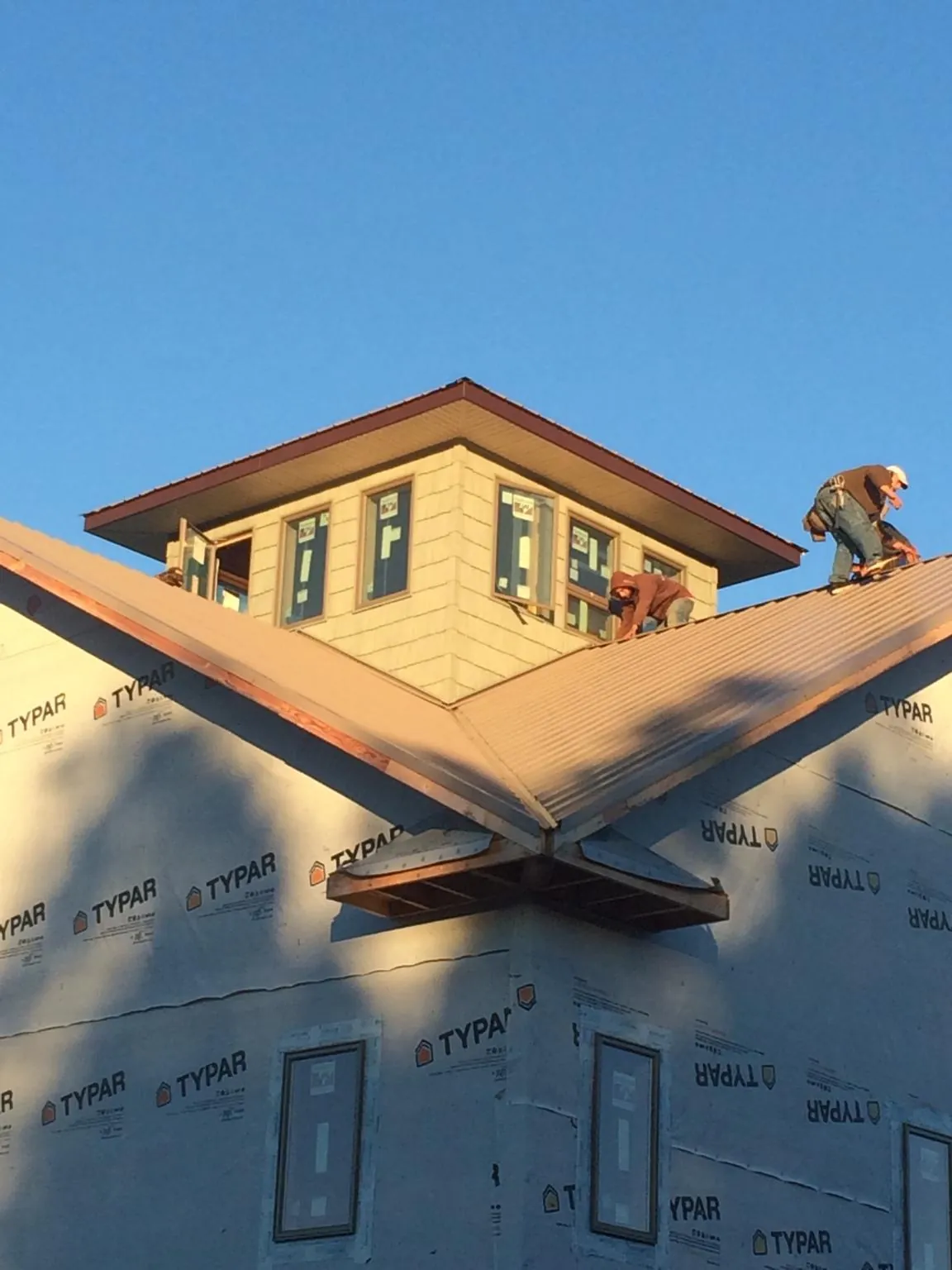 Roofers working around a rooftop cupola on a new metal roof at sunset — Roof Waterproofing in Cerrillos by Roofing Brothers